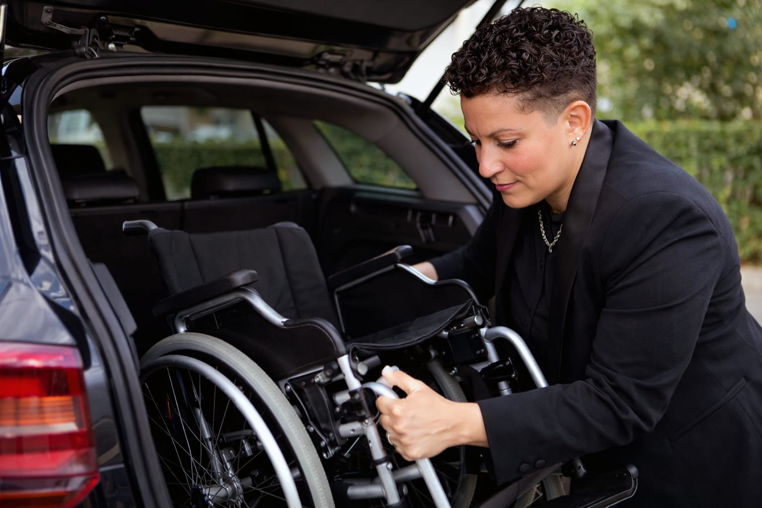 Aurore qui range un fauteuil roulant pliable dans le coffre de la voiture